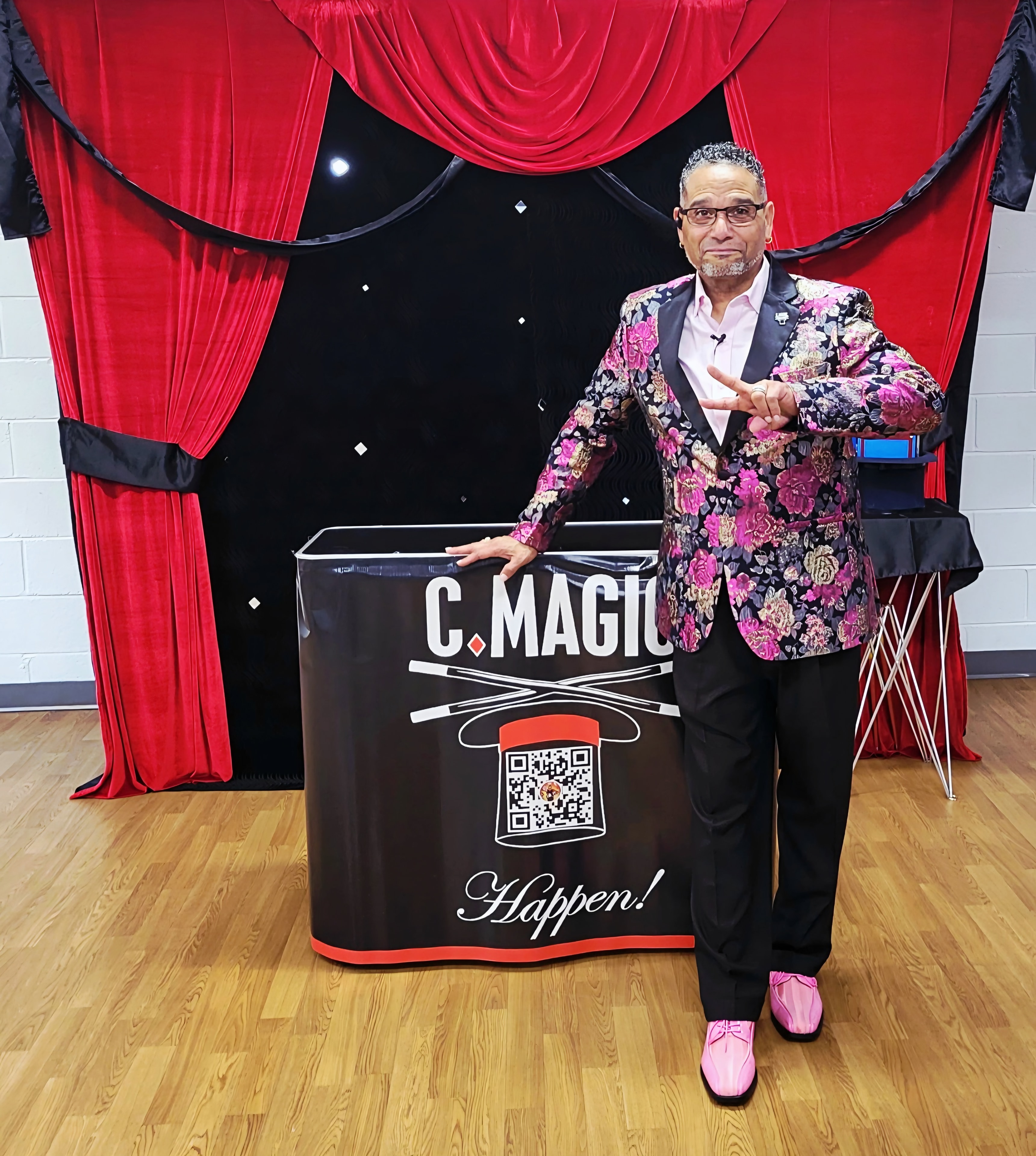 C. Magic performing at event with branded backdrop and red curtains